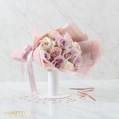 Softly Sweet Roses Bouquet with pink, lavender, and cream roses in sheer pink wrapping and satin ribbon