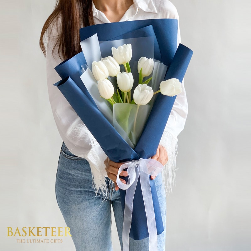 White tulips bouquet in navy and translucent wrap with white ribbon