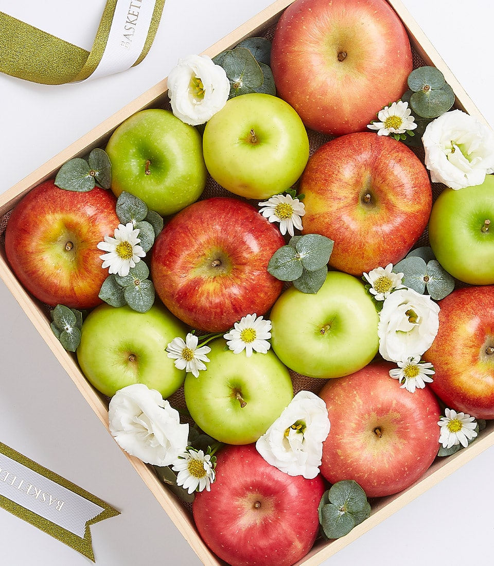 Premium wooden crate filled with red, yellow, and green apples accented with white eustoma flowers and eucalyptus foliage