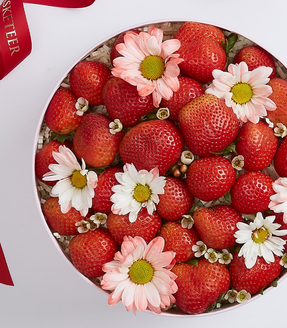 Fresh strawberries and white flowers in pink gift box with red ribbon