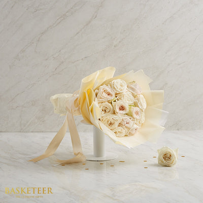 Elegant white O'Hara roses with blush centers wrapped in pale yellow paper, premium fresh flower gift