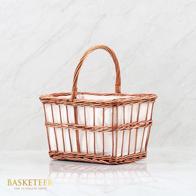 Light brown woven basket with white cloth lining and arched handle for premium gift presentation