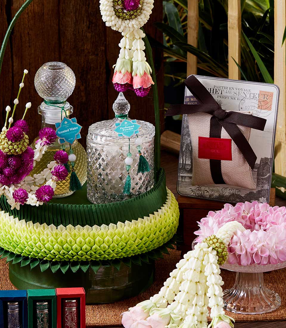 Songkran Thai incense set with scented water, perfumed powder, and fragrance sachets on woven mat with fresh flowers