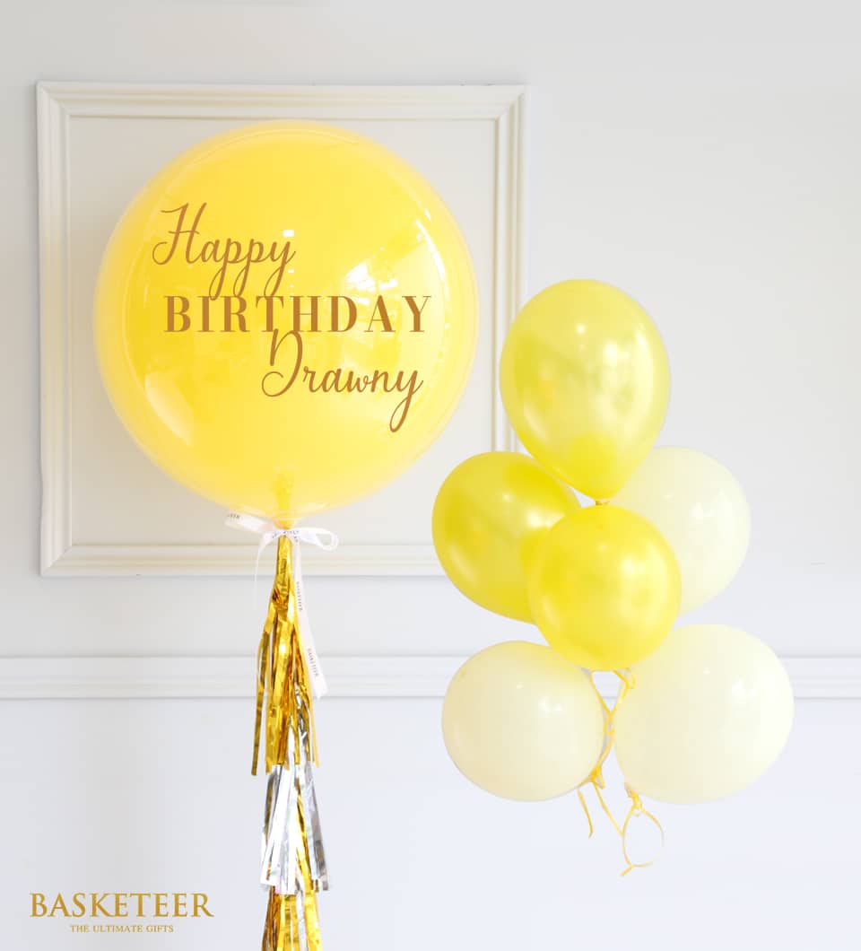 Yellow Happy Birthday balloon with gold and silver tassel garland and cream tone balloon cluster
