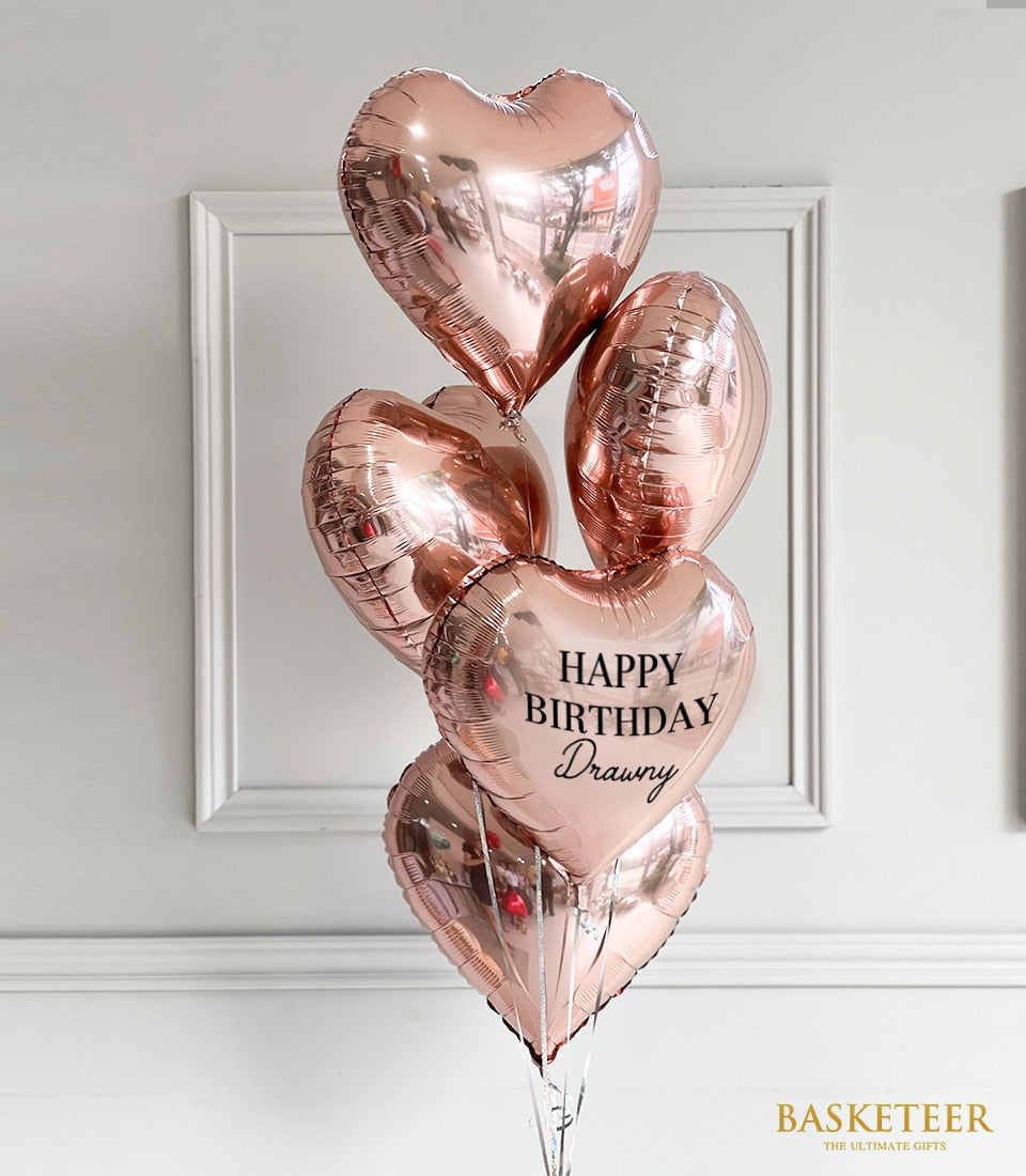 Rose gold heart-shaped foil balloons set with silver ribbons for celebrations