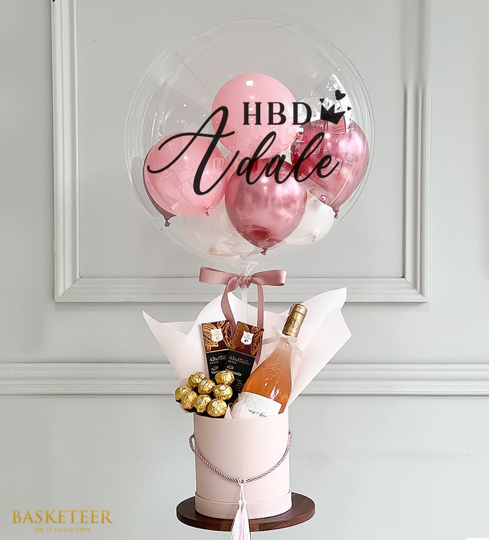 Whispering Angel rosé wine gift set with personalized balloon, dark chocolate, and gold-wrapped truffles in pink