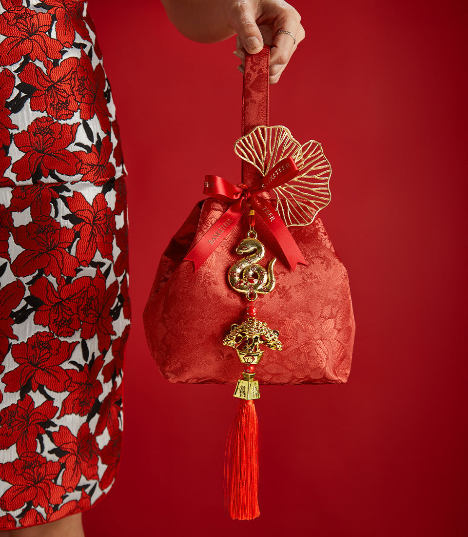 Red fabric gift bag with gold ornaments and silk ribbon bow for Chinese New Year prosperity gifting