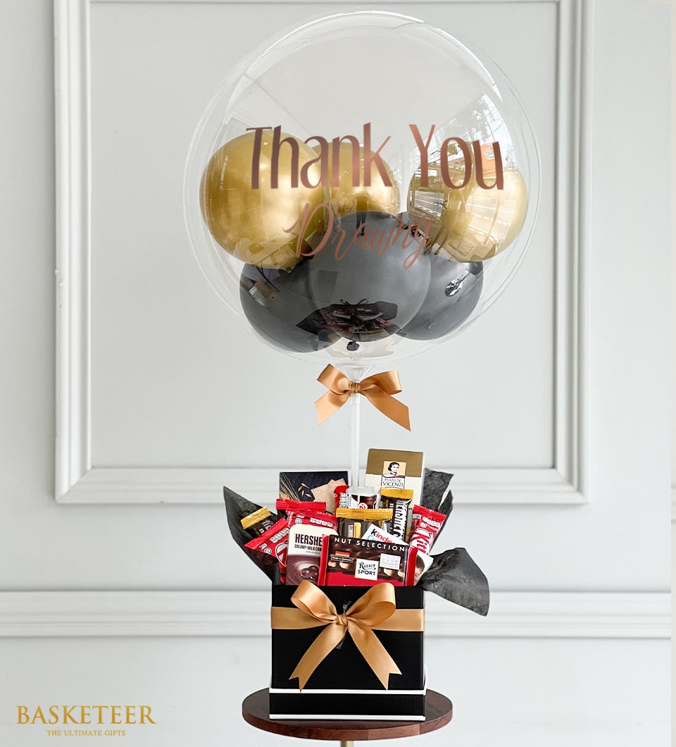 Transparent thank you balloon with gold metallic balloons, paired with black gift box filled with premium chocolates and
