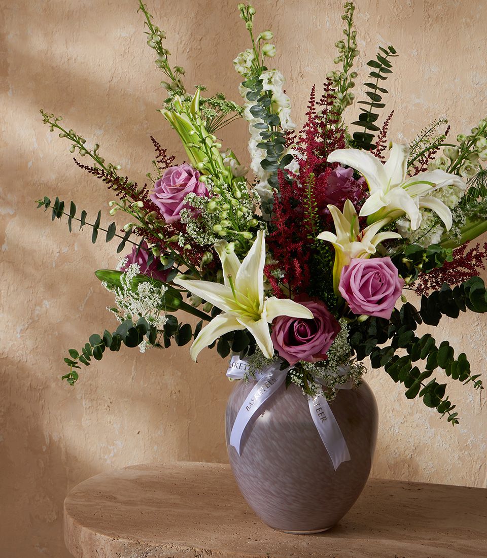 Fresh white lilies and pink roses in marbled grey vase with eucalyptus greenery
