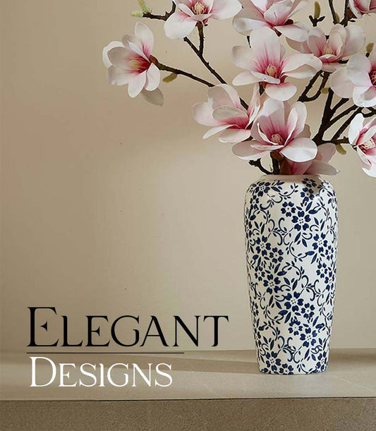 White ceramic vase with blue floral pattern filled with delicate pink and white artificial magnolia flowers