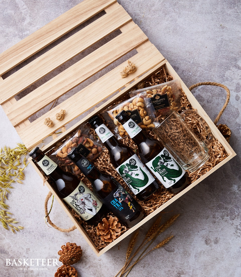 Premium Thai beer selection with cashews, walnuts, and glass mug in wooden gift crate