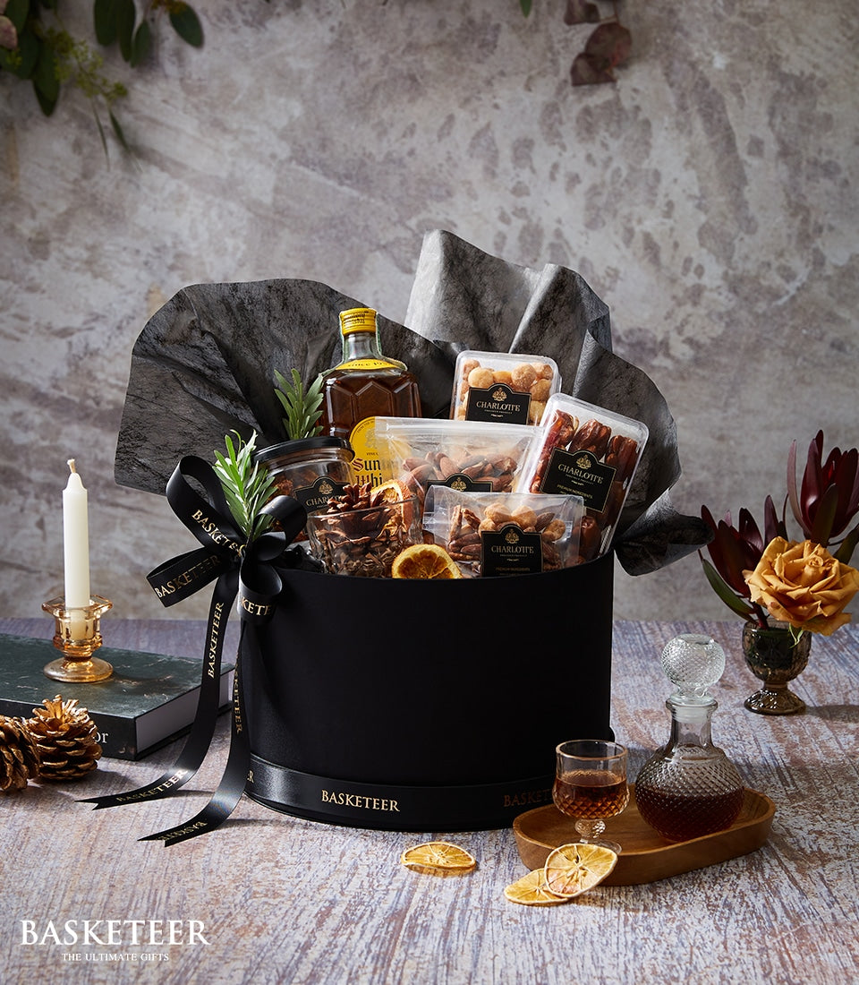 Premium whisky gift box with gourmet treats, nuts, and dried fruits in black and gold packaging