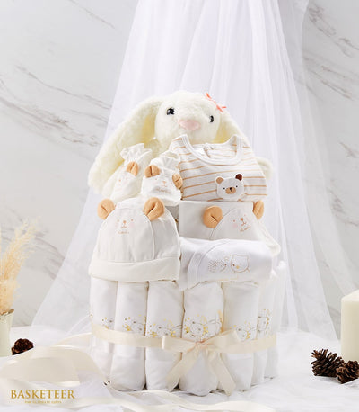 Newborn baby diaper cake with rolled white blankets, plush bunny, and bear-print clothing set
