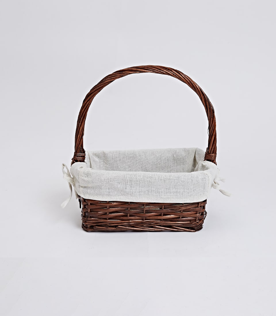 Dark brown wicker gift basket with arched handle and removable cream linen liner