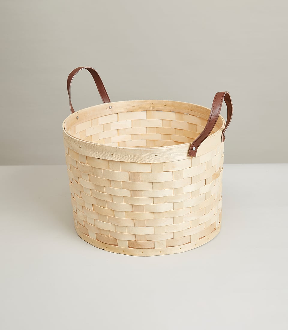 Light woven wooden basket with brown leather handles, perfect for curated gift hampers and artisan collections