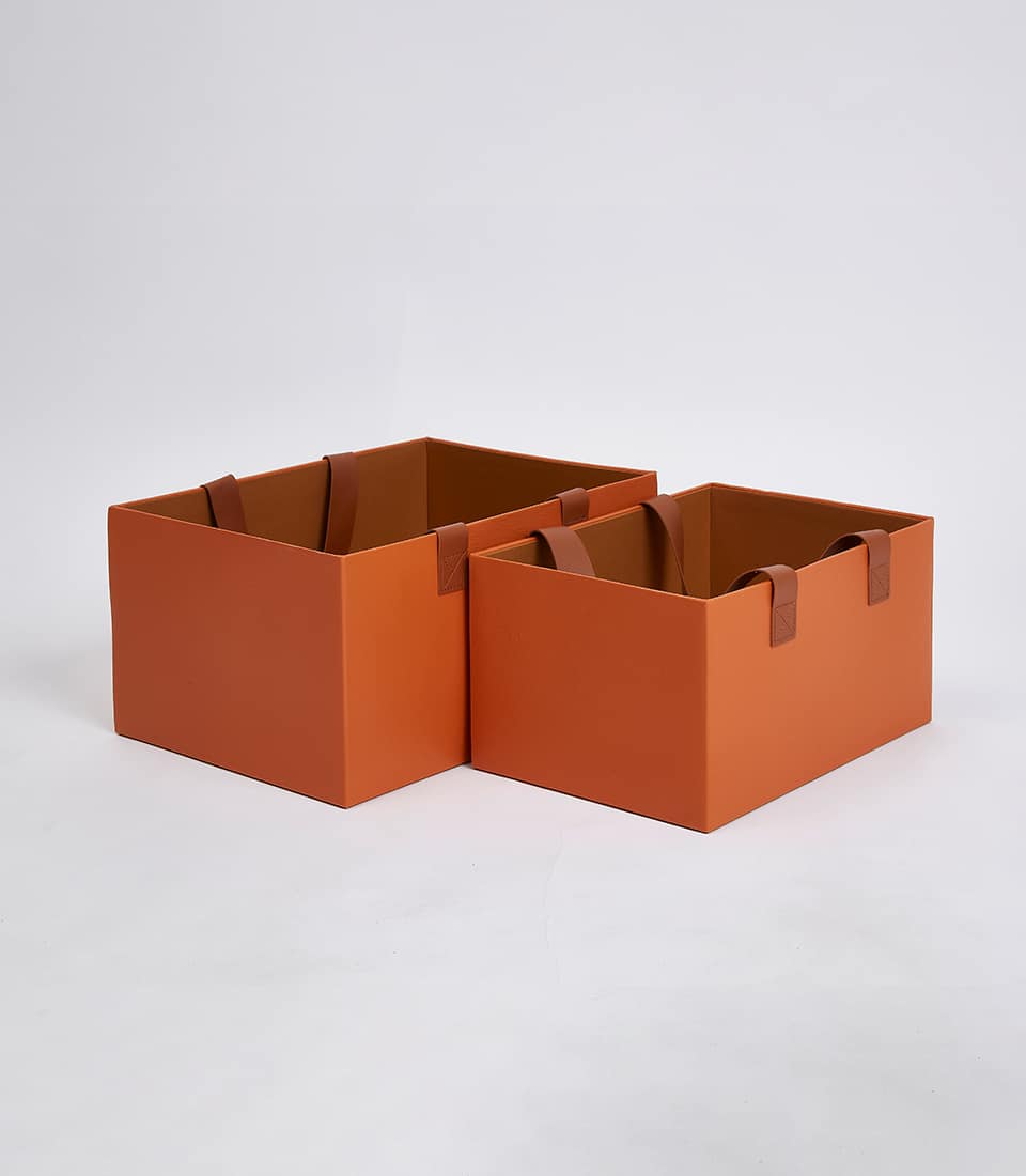 Warm orange nested storage boxes with leather handles, luxury gift packaging