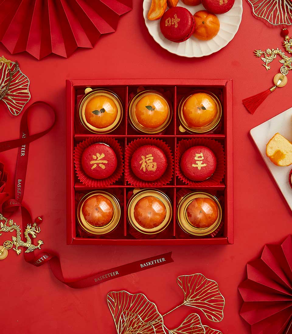 Festive Chinese New Year mandarin sweet gift set with gold-rimmed orange desserts and red prosperity macarons