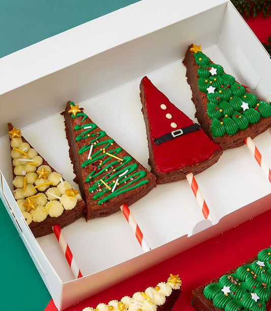 Festive Christmas tree brownie pops with holiday frosting and sprinkles on striped sticks