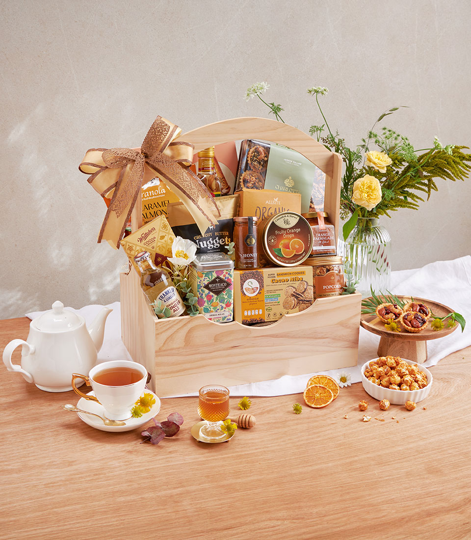 Premium wooden gift hamper filled with gourmet cookies, nuts, tea, honey, and organic pantry items with gold ribbon