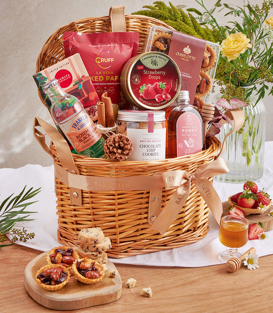 Luxury gourmet gift basket with chocolate chip cookies, honey, artisan treats, and premium snacks in woven wicker