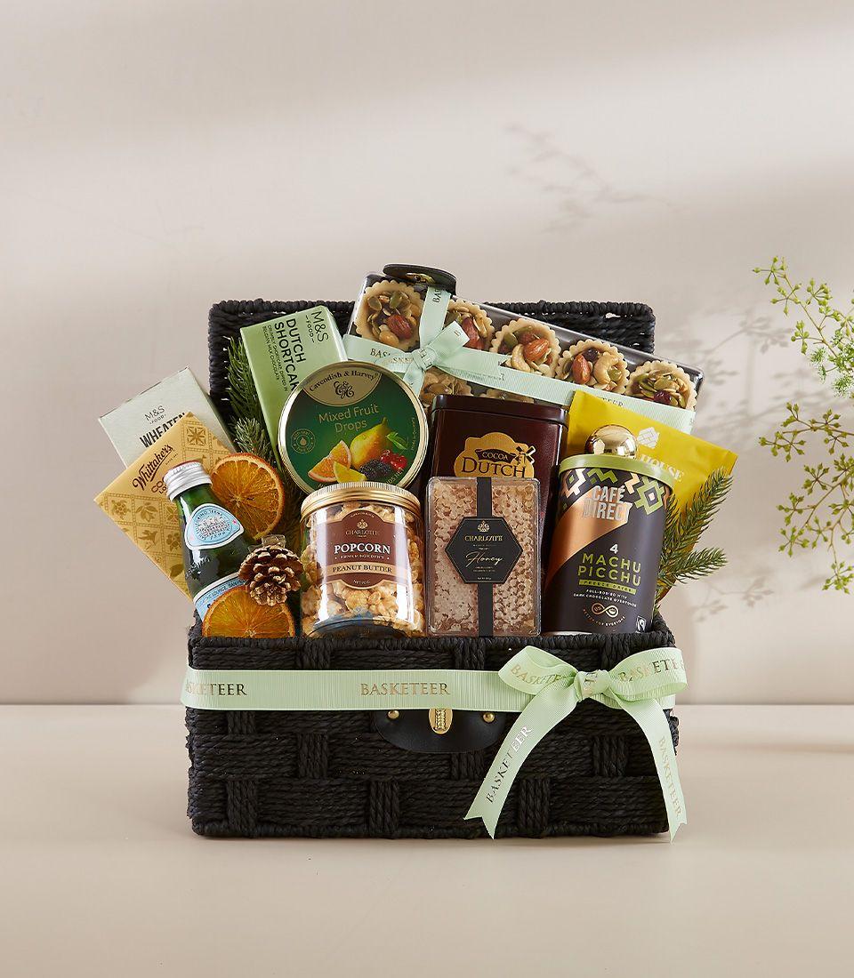 Premium black woven gift basket with gourmet treats, honey, nuts and sparkling water tied with green ribbon for New Year