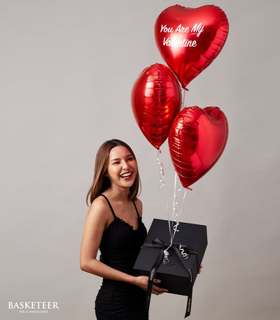 Luxury black gift box with red heart balloons and romantic message for Valentine's Day