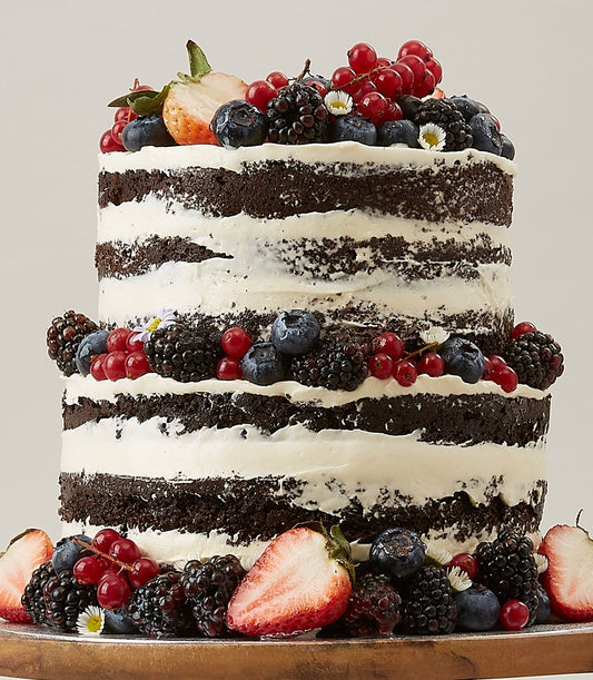 Two-tier naked chocolate cake with fresh berries and white frosting for birthday celebrations