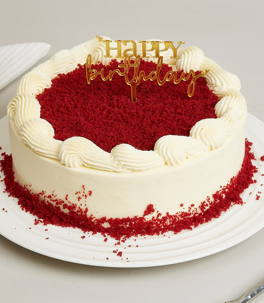 Soft red velvet birthday cake with cream cheese frosting, gold happy birthday topper, and crumb finish on white plate