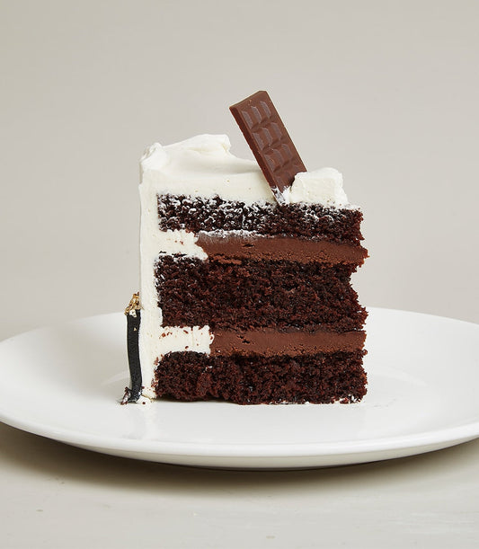 Layered chocolate cake with white frosting and gold leaf detail, mini celebration cake by Charlotte Bakery