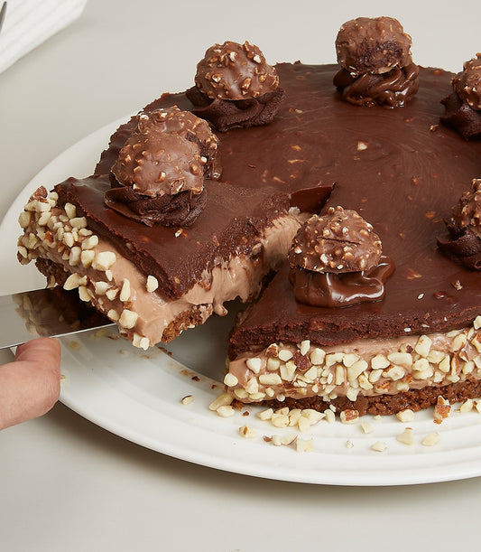 Ferrero Swirl Cheesecake with chocolate ganache, hazelnut pralines, and creamy layers on white plate