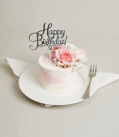 Mini pink rose celebration cake with fresh roses and white baby's breath on white plate
