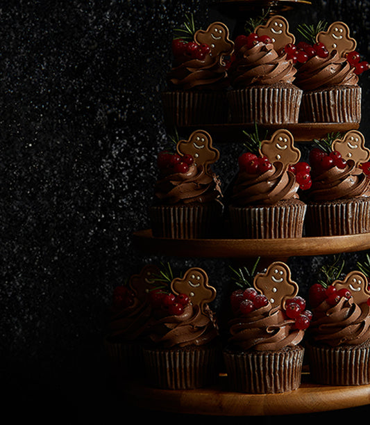 Chocolate ganache gingerbread cupcakes with currants and rosemary on tiered wooden stand
