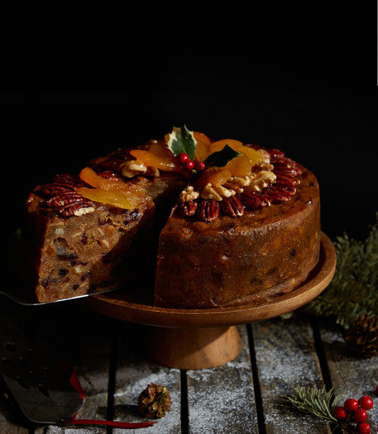 Traditional British fruitcake with pecans and dried apricots, garnished with holly for Christmas