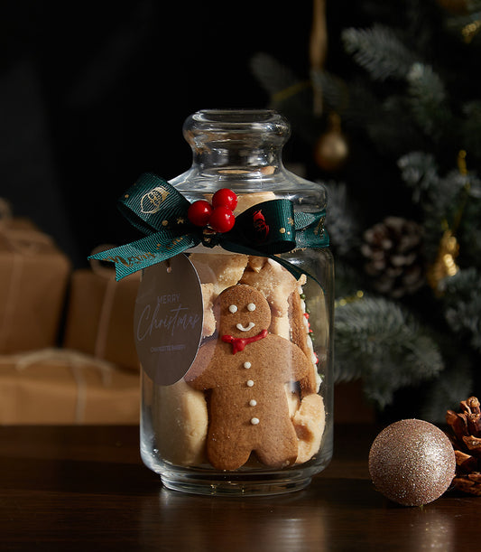 Festive Christmas cookies jar with gingerbread man, tied with dark green ribbon and berry accent