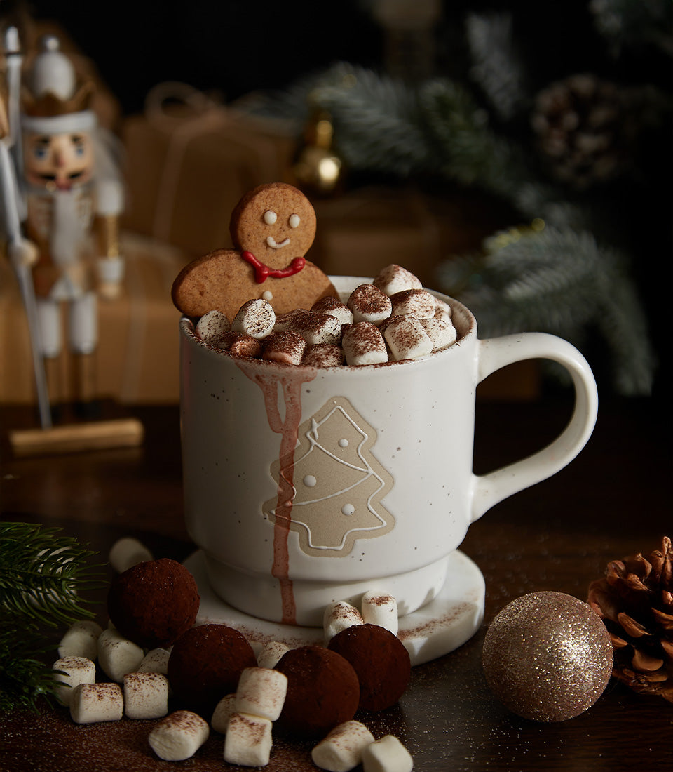 Festive hot chocolate gift set with gingerbread cookie, marshmallows, chocolate truffles, and embossed Christmas mug