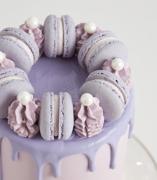 Purple drip macaron birthday cake with lavender frosting and pearl accents, artisan celebration design