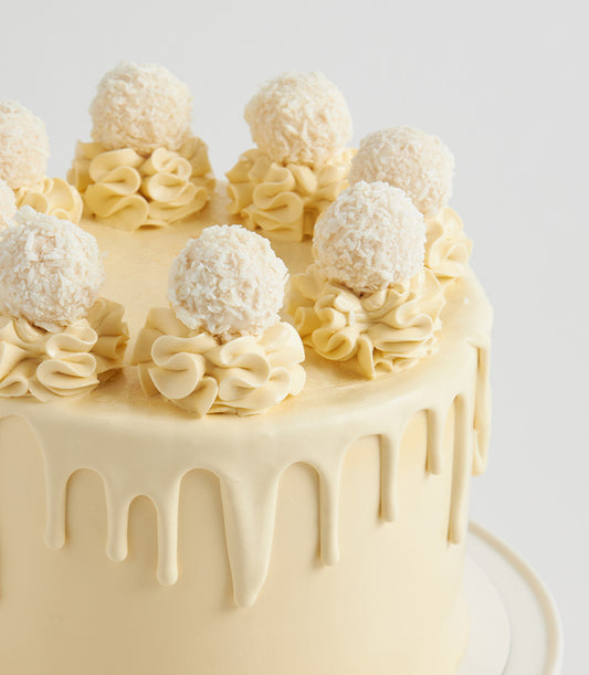 White Ferrero cream cake with coconut truffles and white chocolate drip for birthdays