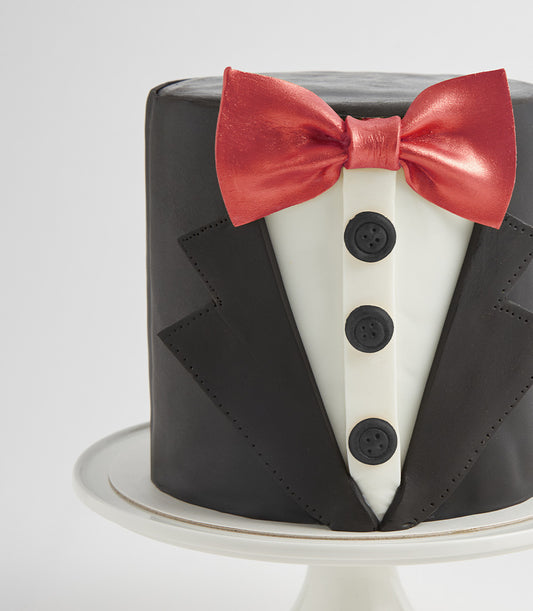 Gentleman Tuxedo Cake with black fondant suit jacket, white shirt front, and red bow tie by Charlotte Bakery