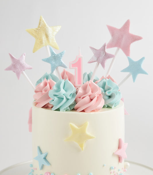 Pastel star two-tier first birthday cake with pink and blue frosting swirls and glittery star toppers