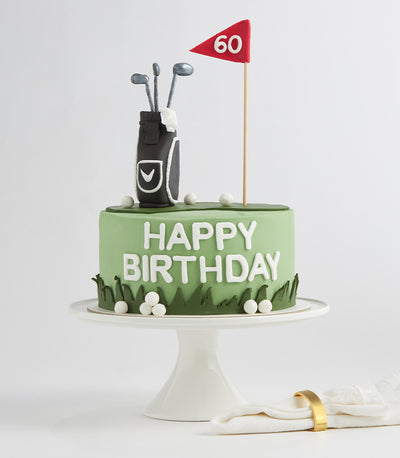 Light green golf course cake with fondant lettering, fondant golf bag, clubs, and flag on white stand
