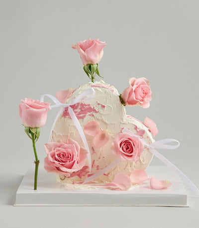 Heart-shaped strawberry cake with fresh pink roses and white ribbons
