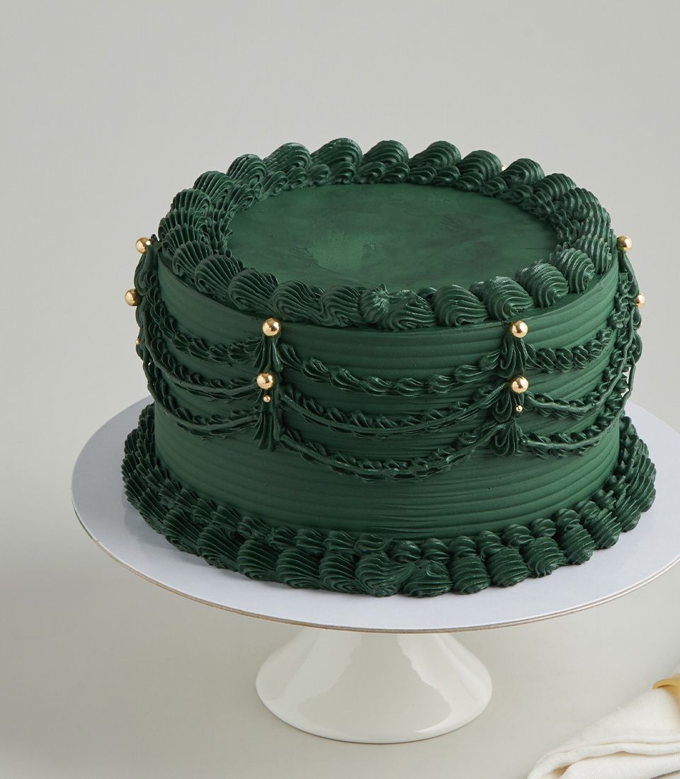 Emerald green buttercream cake from Charlotte Bakery, a perfect custom cake Bangkok choice. Draped icing and gold pearls add vintage charm.