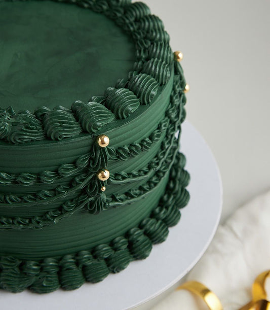 Charlotte Bakery artisan cake: Emerald green buttercream, draped piping detail, and gold pearls. Order your custom cake in Bangkok today!