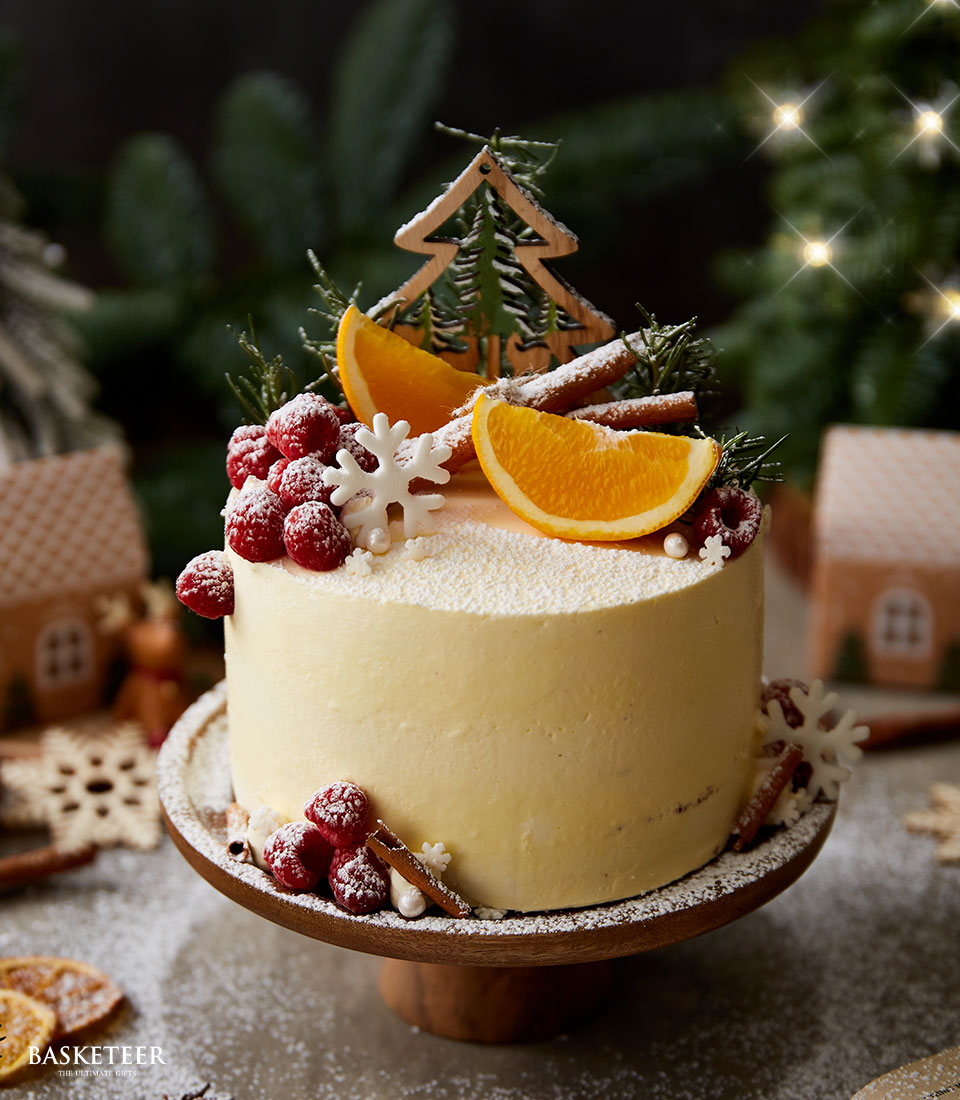 Winter Wonderland orange cake with raspberries, cinnamon and snowflake decorations on wooden stand