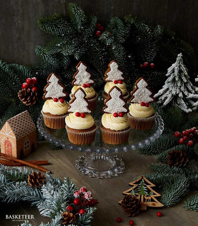 Six gingerbread Christmas tree cupcakes with cream frosting and festive sprinkles on glass stand