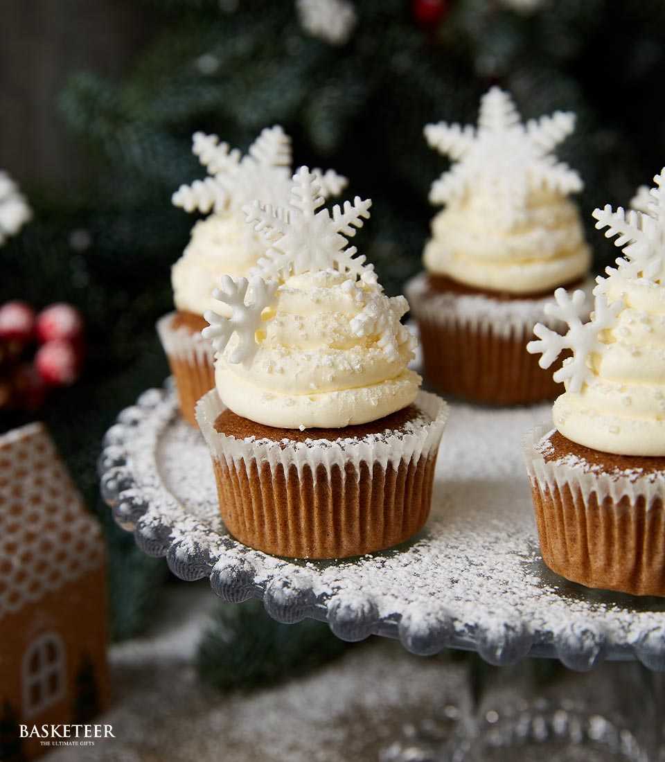 Festive vanilla cupcakes with white frosting and snowflake decorations on glass stand, Christmas bakery gift