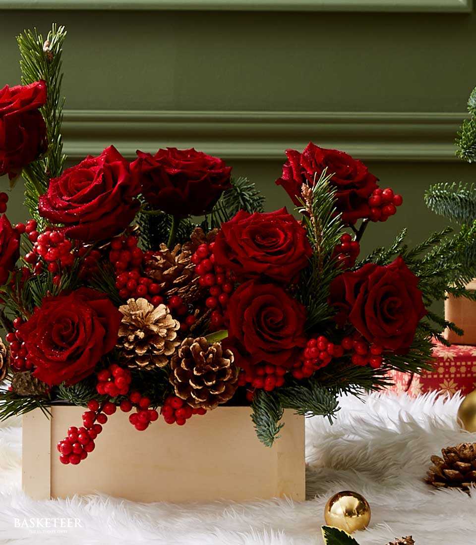 Deep red roses with pine, berries, and gold pinecones in wooden box Christmas arrangement