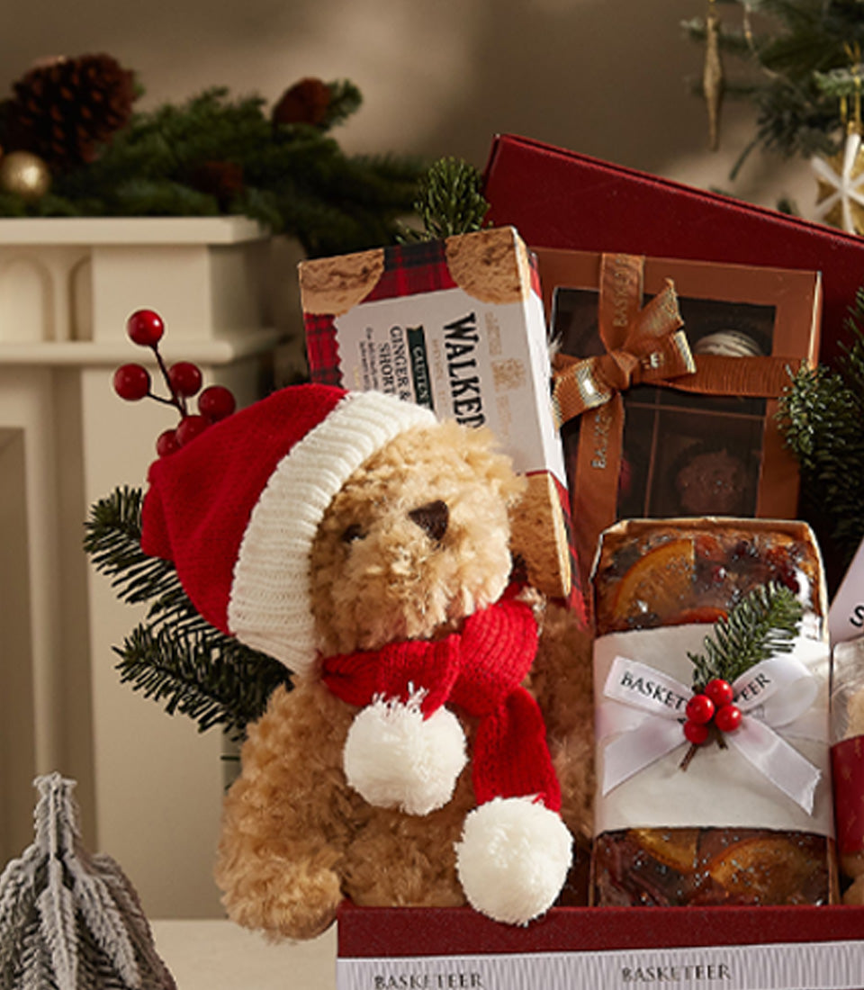 Festive Christmas gift box with teddy bear, shortbread, chocolates, and fruit cake in red container