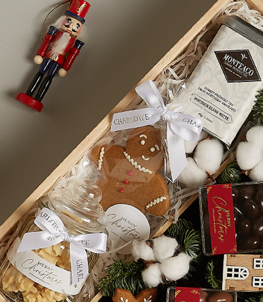 Wooden Christmas hamper with gingerbread cookie, festive tea tin, chocolate truffles, and nutcracker ornament