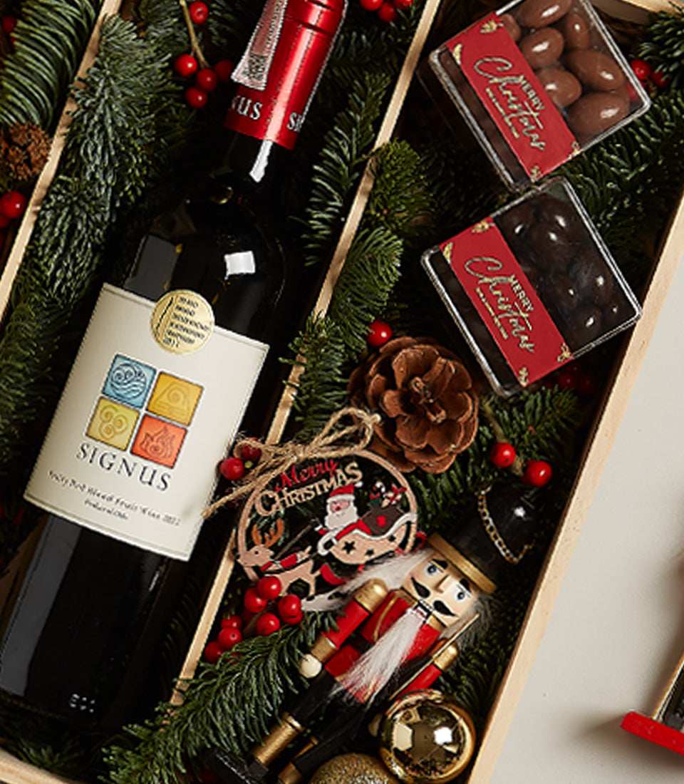 Premium red wine and artisan chocolates in festive wooden box with holiday decorations